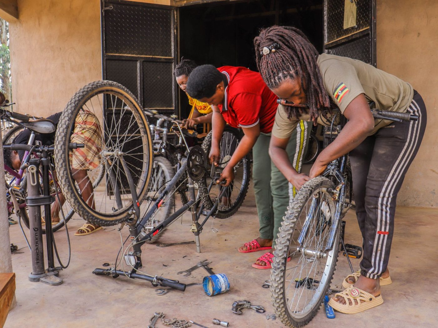 Three women collaboratively repairing bicycles in an indoor workshop.